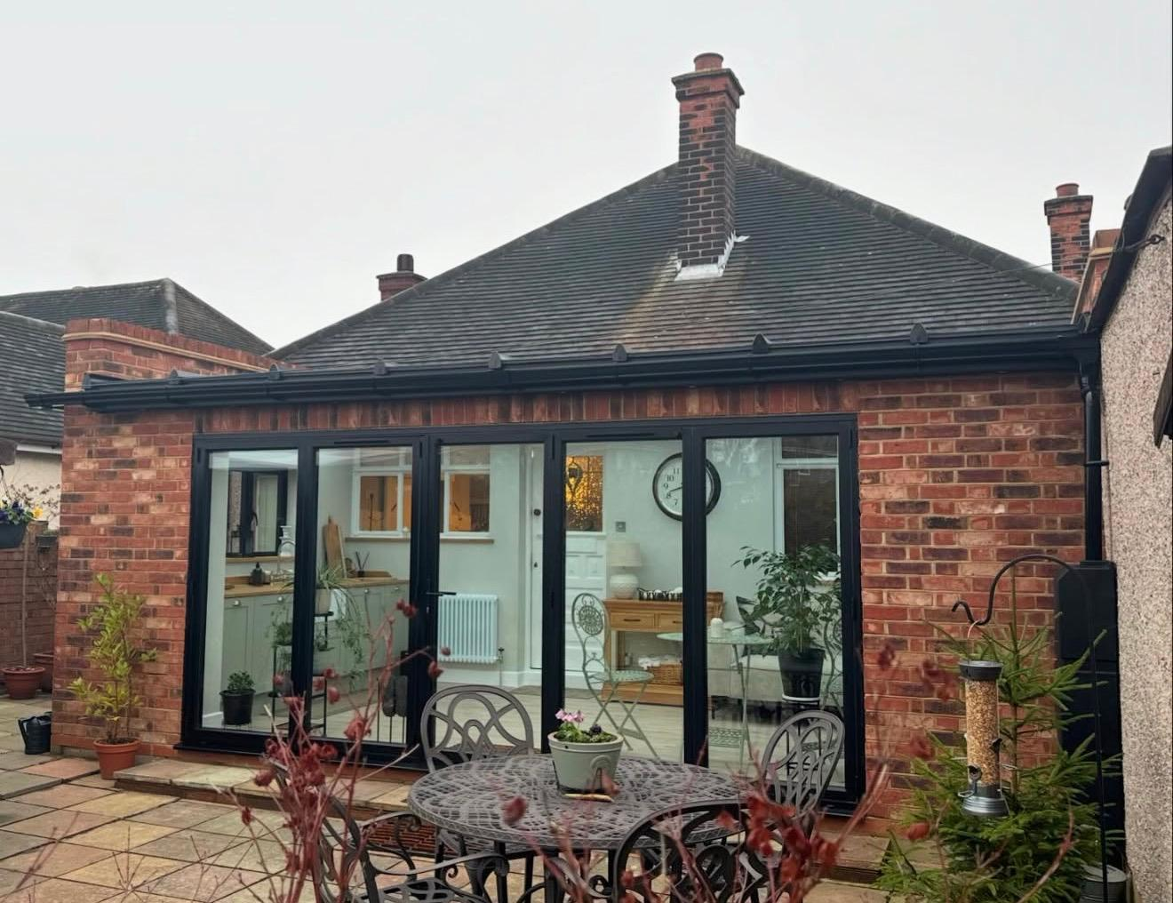 Refurbished rear bungalow with red brick, anthracite bifold doors and new tiled hipped roof in Essex